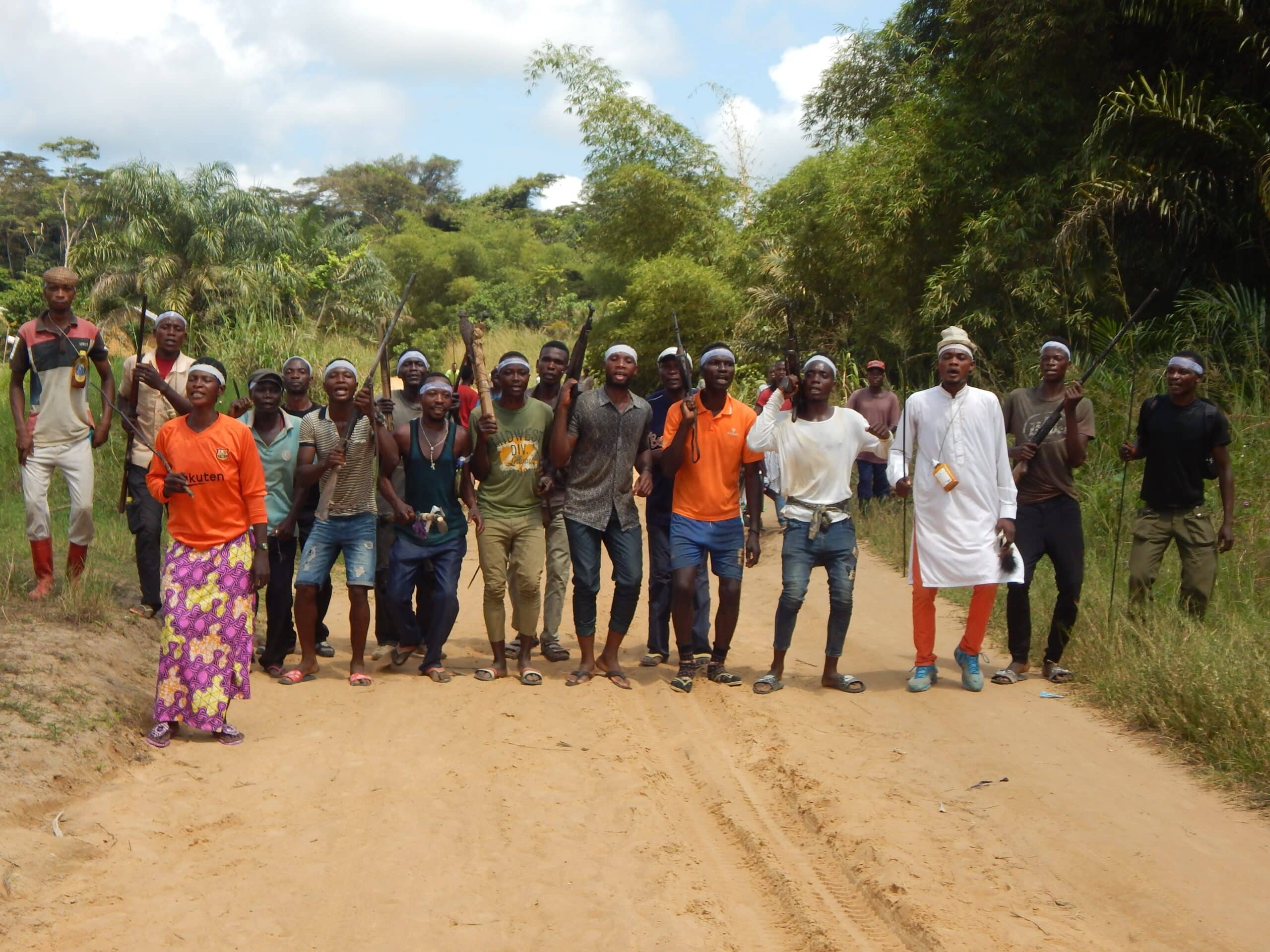A group of dancing people on a dirt road.